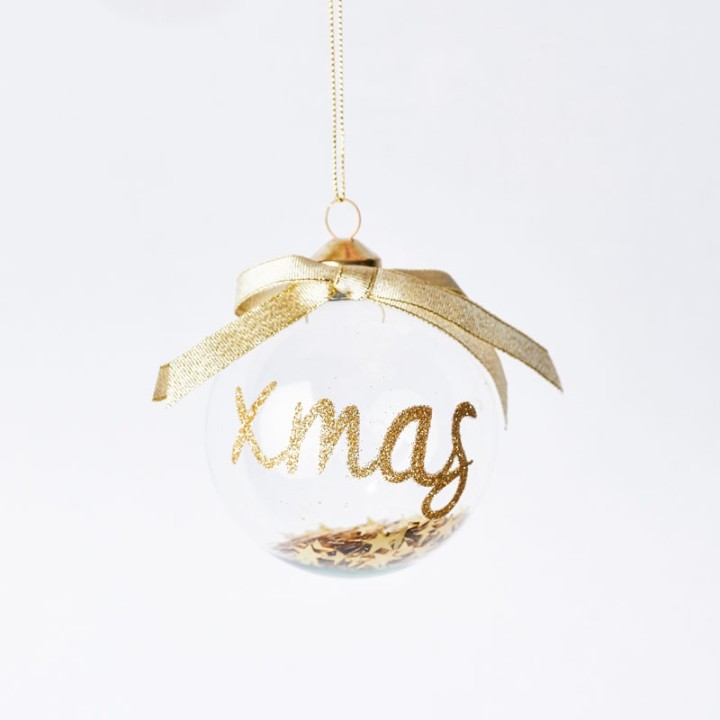 Boule de Noël transparente ornée de paillettes dorées et d'un ruban élégant.