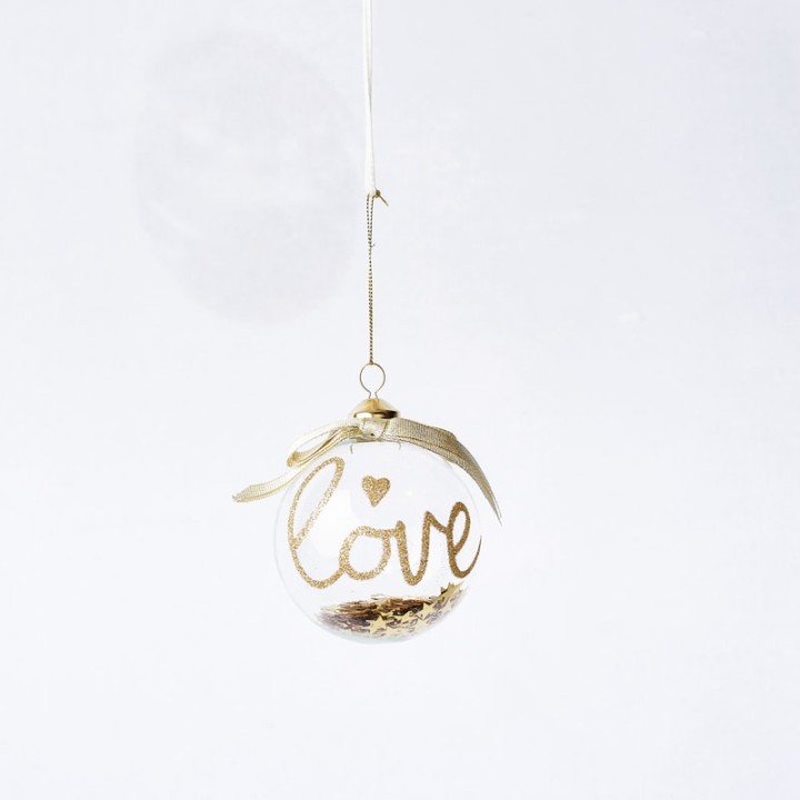 Boule transparente suspendue, ornée de paillettes dorées et du mot "love".