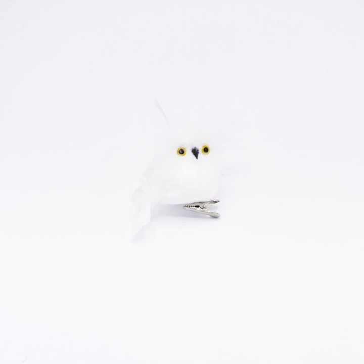 Hibou en feutre blanc avec yeux dorés, posé sur une pince argentée.