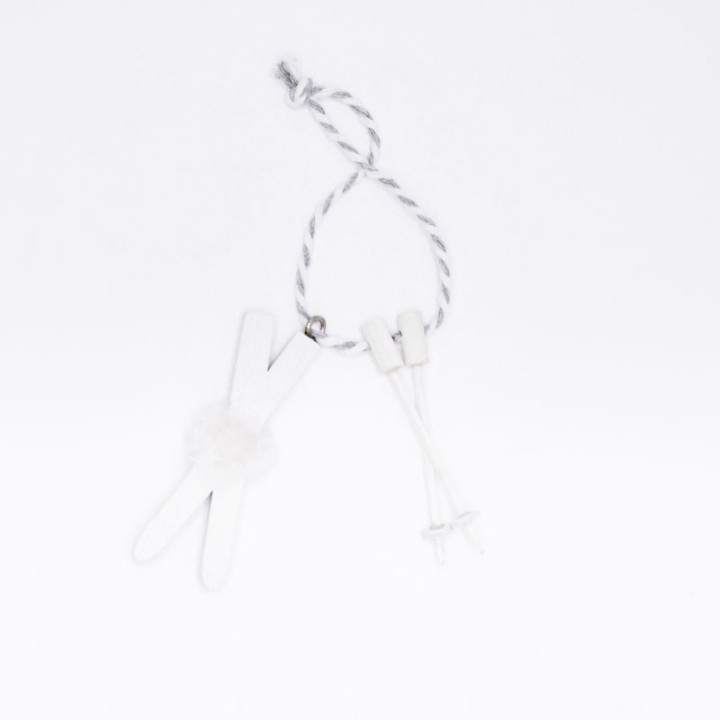 Pince à linge blanche attachée à une corde, avec un pompon doux et des embouts en plastique.