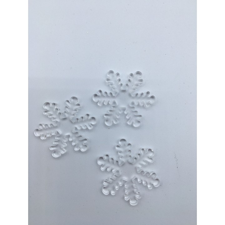 Flocons de neige en plastique transparent sur fond blanc, délicats et sculptés.