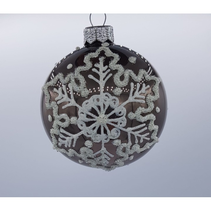 Boule de Noël ornée de motifs en relief, scintillante sur fond clair.