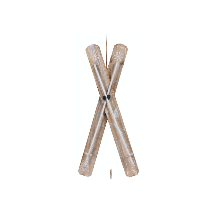 Deux skis en bois croisés, décorés de flocons, avec des fixations blanches.