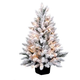 Sapin de Noël enneigé, illuminé, avec des branches douces et un pot noir.