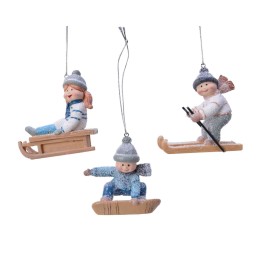 Trois figurines d'enfants en hiver, jouant avec des luges et des skis, décorées de paillettes.