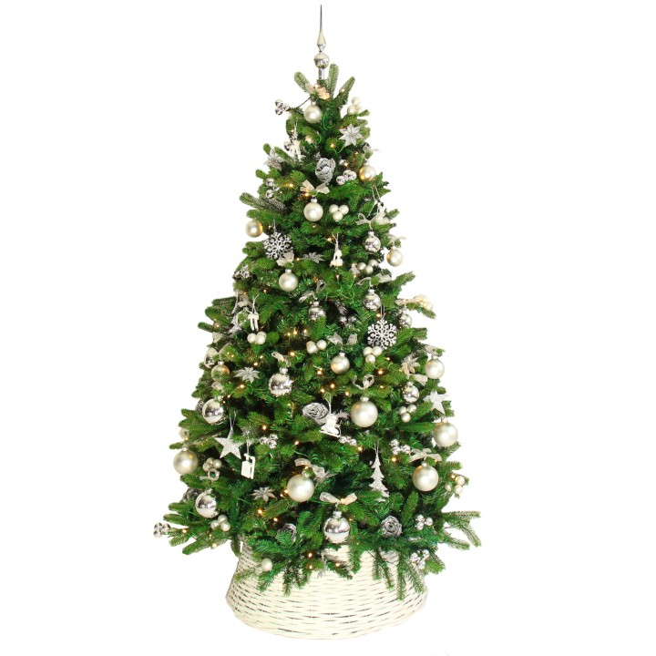 Sapin de Noël décoré de boules argentées et blanches, reposant dans un panier tressé.