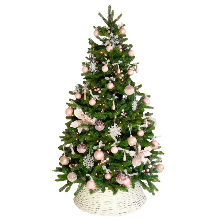 Sapin de Noël vert décoré de boules roses et de flocons, reposant dans un panier blanc.