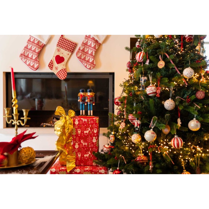 Noël chaleureux avec un sapin décoré, des cadeaux colorés et des chaussettes suspendues.