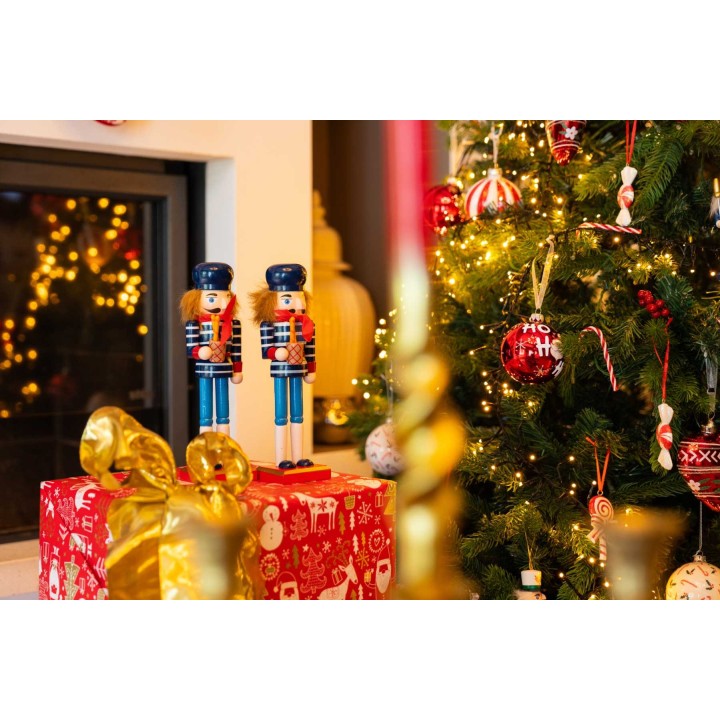 Soldats de bois colorés près d'un sapin décoré et de cadeaux festifs scintillants.