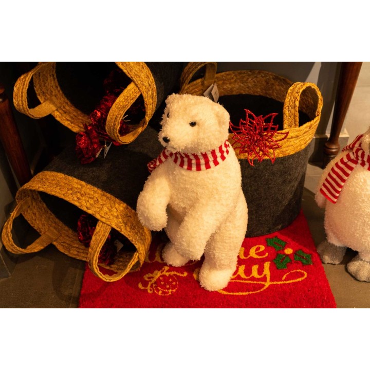 Ours en peluche blanc avec écharpe, entouré de paniers tressés et d'un tapis décoratif.