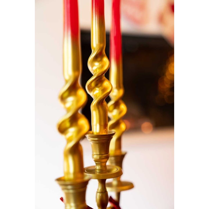 Bougeoirs dorés au design spiralé, ornés de bougies rouges éclatantes.