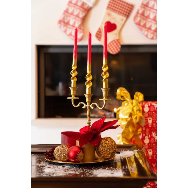 Bougeoir doré avec trois bougies rouges, décor festif et ambiance chaleureuse.