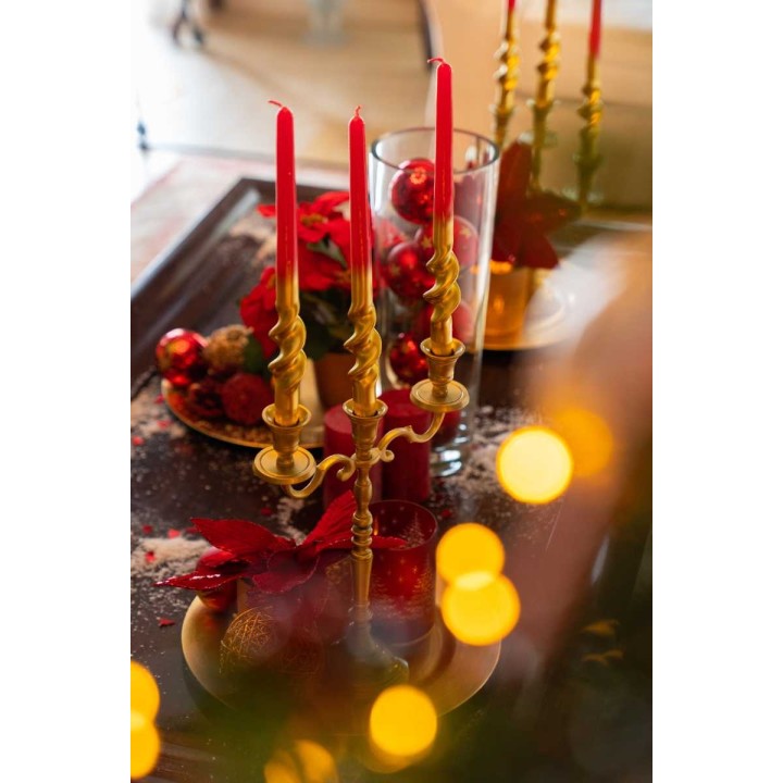 Bougies rouges sur un chandelier doré, décor festif avec pommes et feuillage.