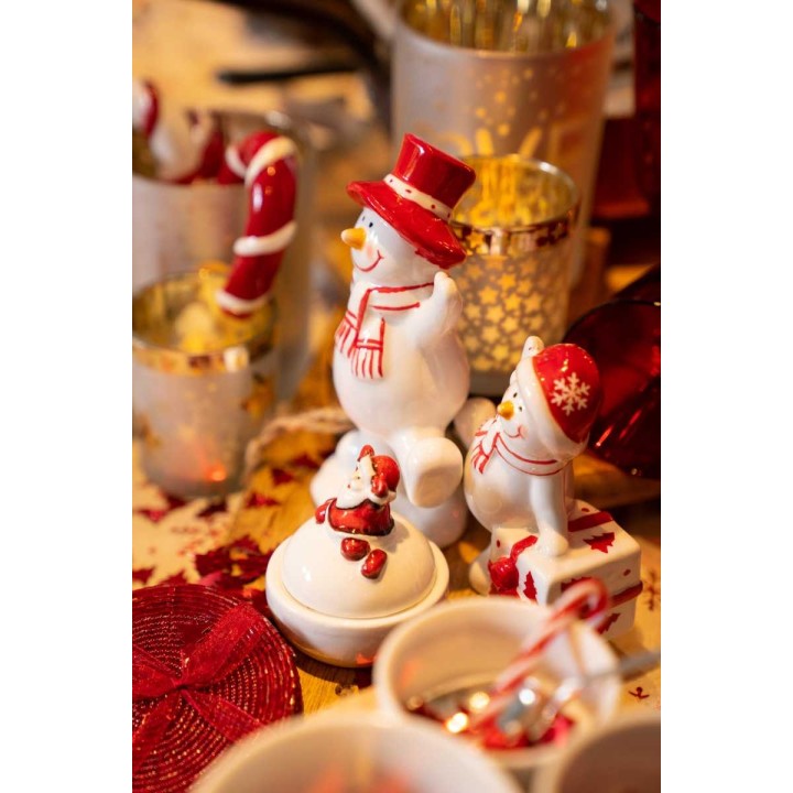 Décor festif avec des bonhommes de neige en céramique et des accents rouges et dorés.