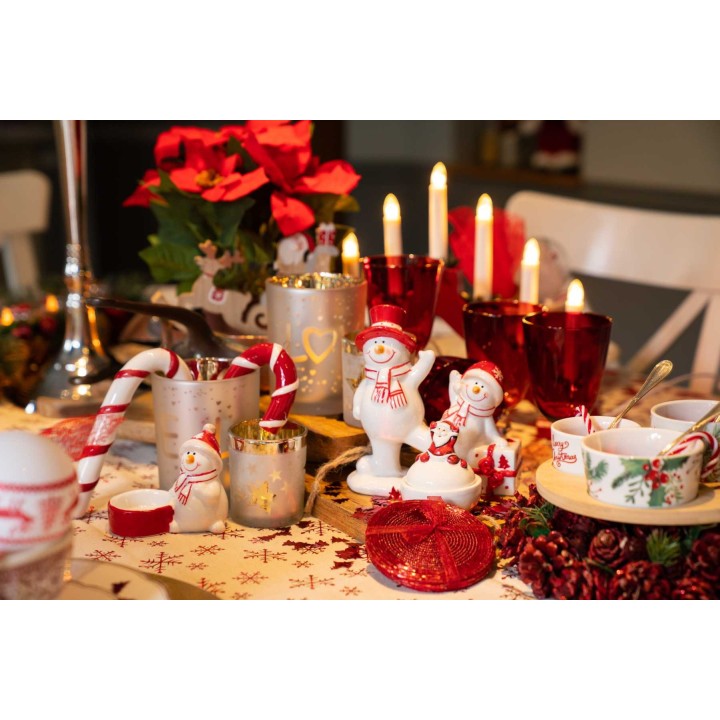 Table festive ornée de décorations hivernales, bougies rouges et figurines de bonhommes de neige.