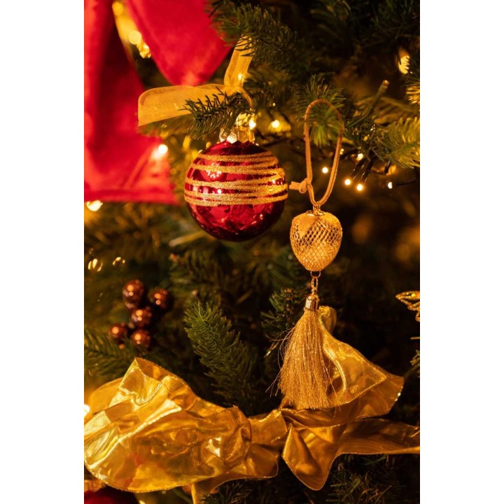 Boules rouge et dorée scintillantes, guirlandes et rubans sur un sapin lumineux.
