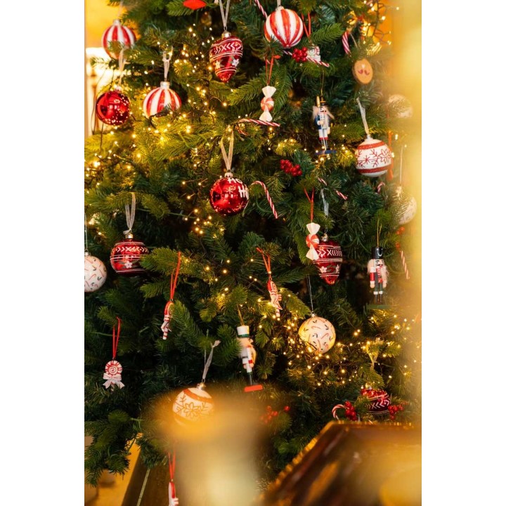 Sapin décoré de boules rouges, guirlandes lumineuses et ornements festifs.