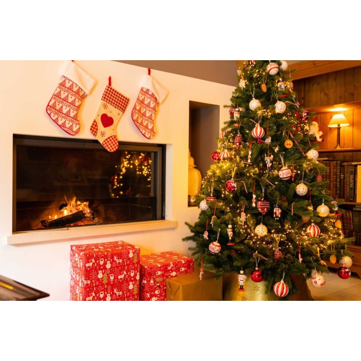 Un sapin décoré, des chaussettes rouges, des cadeaux festifs près d'une cheminée chaleureuse.