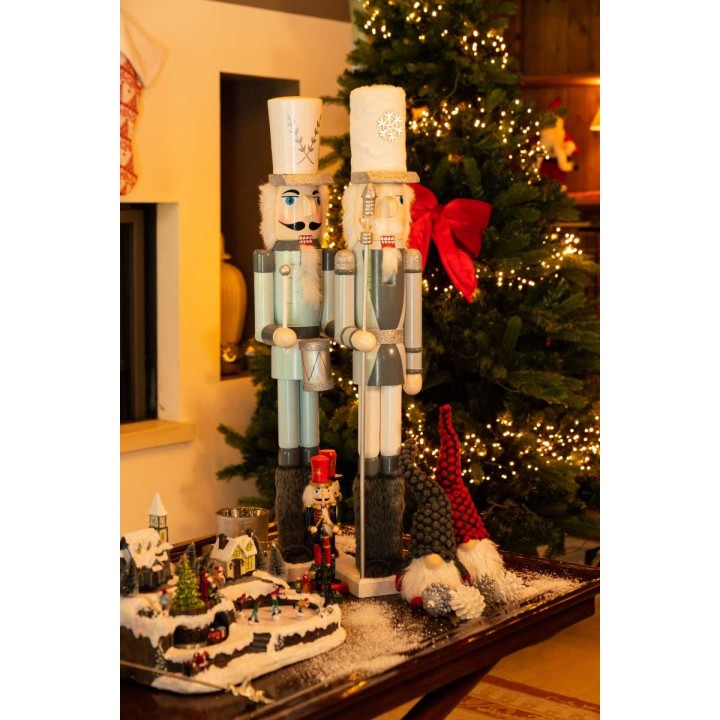 Figurines de soldats de bois colorés, décorations festives et sapin illuminé en arrière-plan.