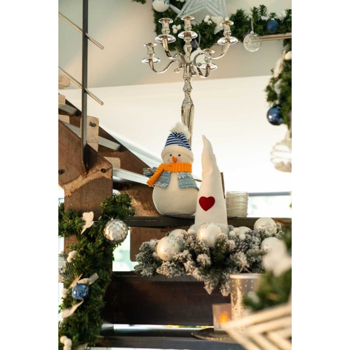Escalier décoré de guirlandes et ornements festifs, avec un bonhomme de neige en peluche.