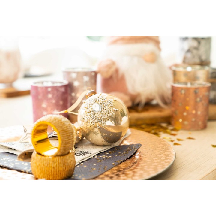Décor festif avec des boules dorées, paillettes et bougies colorées sur une table élégante.