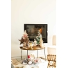 Décor chaleureux avec sapins miniatures, étoile en bois et feu crépitant.