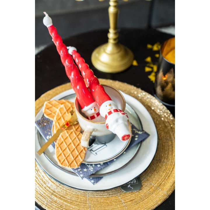 Bougie rouge en forme de sapin dans une tasse, décorée de biscuits et assiette dorée.