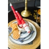 Bougie rouge en forme de sapin dans une tasse, décorée de biscuits et assiette dorée.