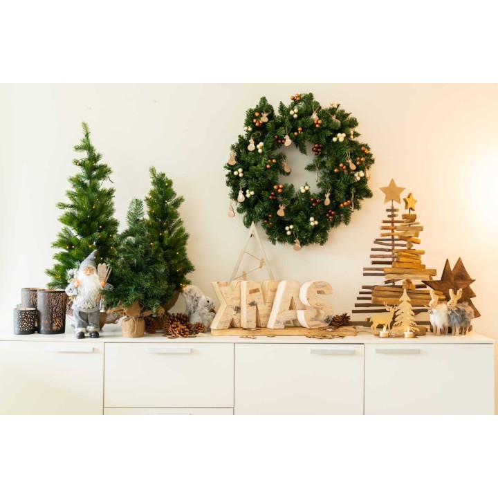 Décoration festive avec sapins, couronne, et éléments en bois et dorés. Ambiance chaleureuse.