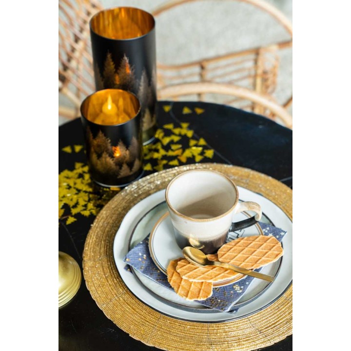 Une table élégamment dressée avec une tasse, des gaufrettes et des bougies dorées.