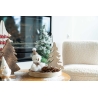 Décor festif avec sapins en bois, un bonhomme de neige et des cônes de pin sur une table.
