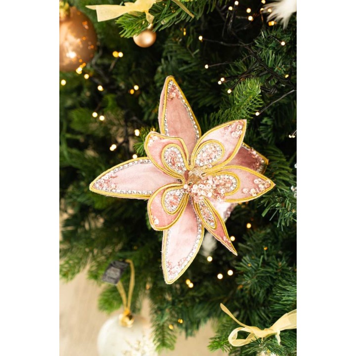 Fleur décorative rose ornée de sequins, posée sur un sapin de Noël verdoyant.