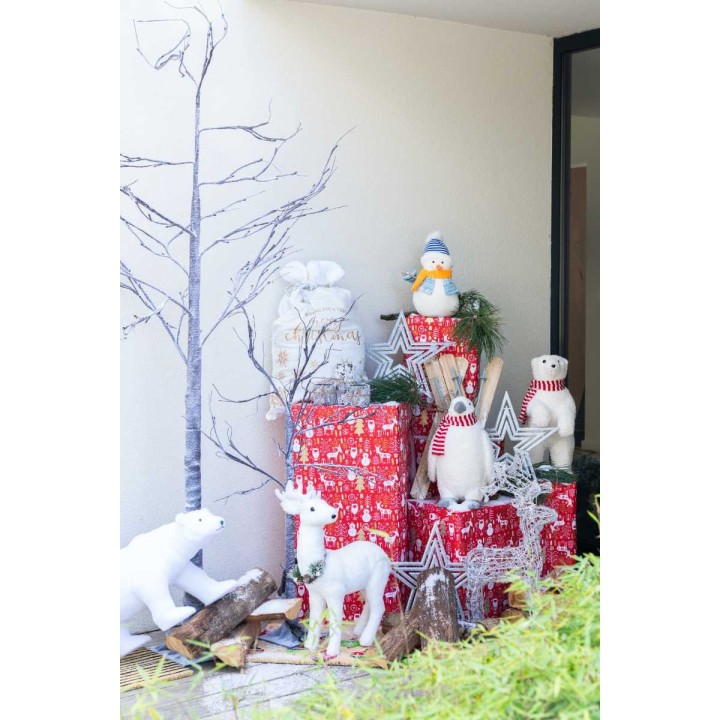 Décor festif avec cadeaux colorés, animaux en peluche et branches blanches.