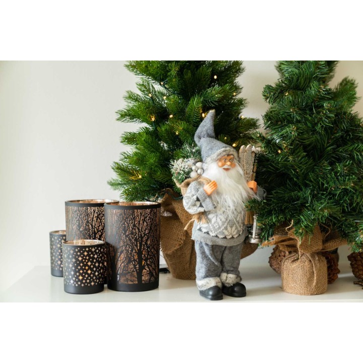 Un gnome festif près de sapins et de lanternes décoratives en bois.