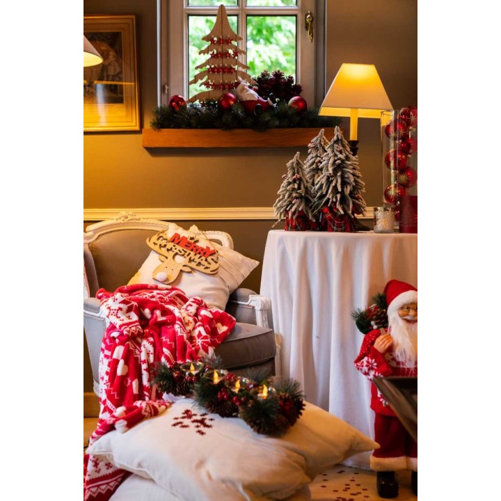 Ambiance chaleureuse de Noël avec décorations, coussins et lumière douce.