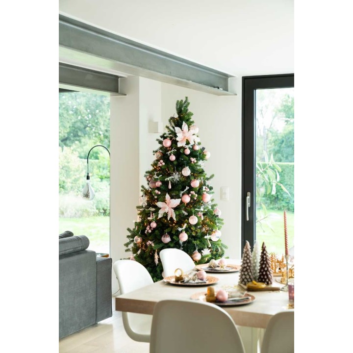 Sapin de Noël décoré de fleurs roses et boules brillantes, ambiance chaleureuse et moderne.