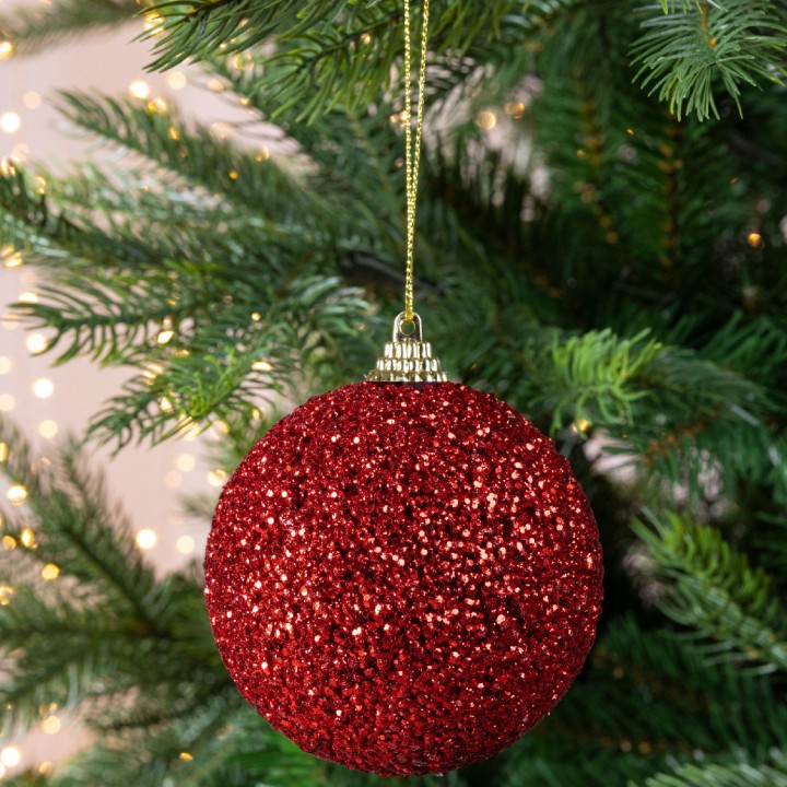 Boule de Noël rouge étincelante suspendue à un sapin décoré.