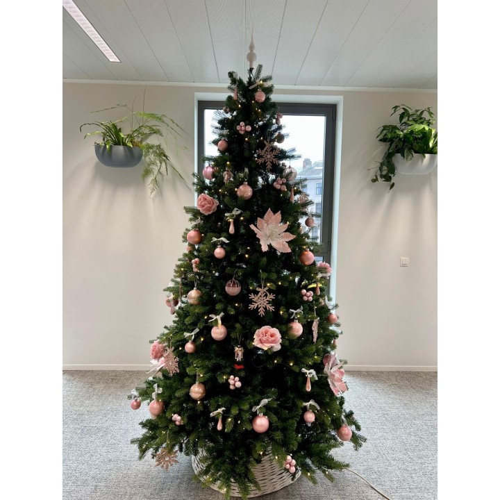 Sapin décoré de rose et blanc, ornements floraux et boules brillantes, ambiance chaleureuse.