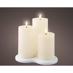 Trois bougies blanches allumées sur un support élégant, créant une ambiance chaleureuse.