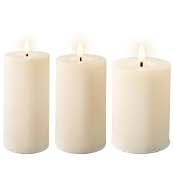 Trois bougies blanches cylindriques allumées, éclairant doucement un environnement calme.