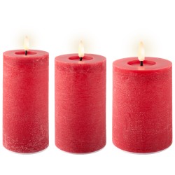 Trois bougies cylindriques rouges, allumées, diffusent une douce lumière chaleureuse.