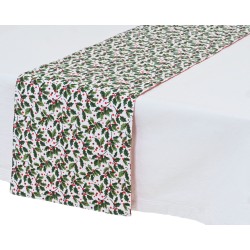 Nappe blanche avec chemin de table à motifs de houx rouges et verts sur fond clair.