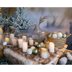 Ambiance chaleureuse avec bougies, ornements dorés et végétation hivernale.