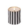 Bougie cylindrique avec rayures noires et blanches, bord doré, flamme dansante.