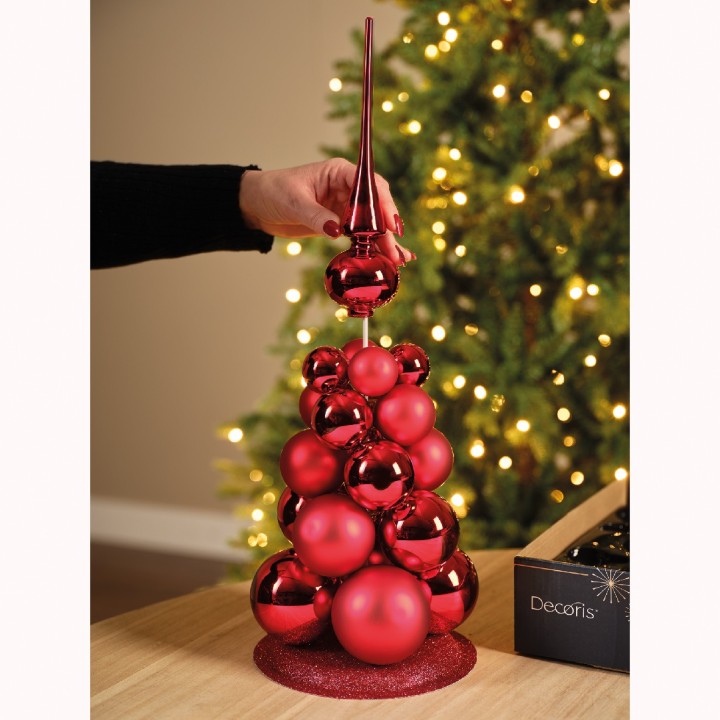 Un sapin miniature en boules rouges brillantes, décoré d'une pointe élégante.