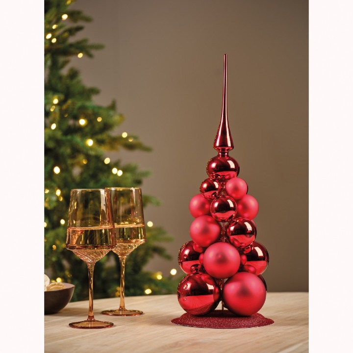 Arbre de Noël rouge brillant, accompagné de flûtes dorées sur une table festive.