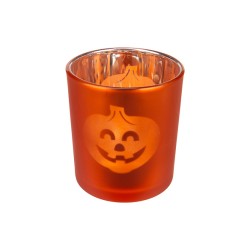 Bougie orange en verre avec un visage de citrouille souriant gravé.