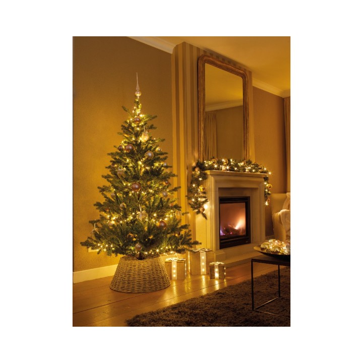 Un sapin illuminé près d'une cheminée, ambiance chaleureuse et festive.