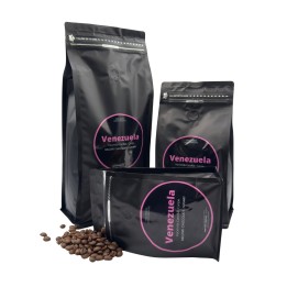 Trois sachets noirs de café avec étiquettes roses, entourés de grains de café.