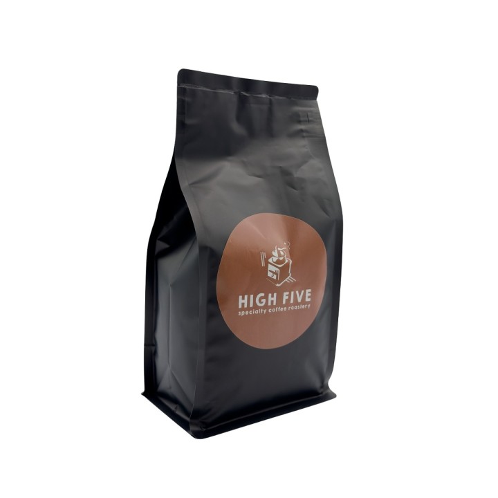 Sachet noir élégant avec un logo rond marron, design moderne pour café.